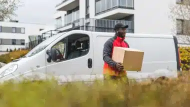 package delivery person - in front of white truck with cardboard package.