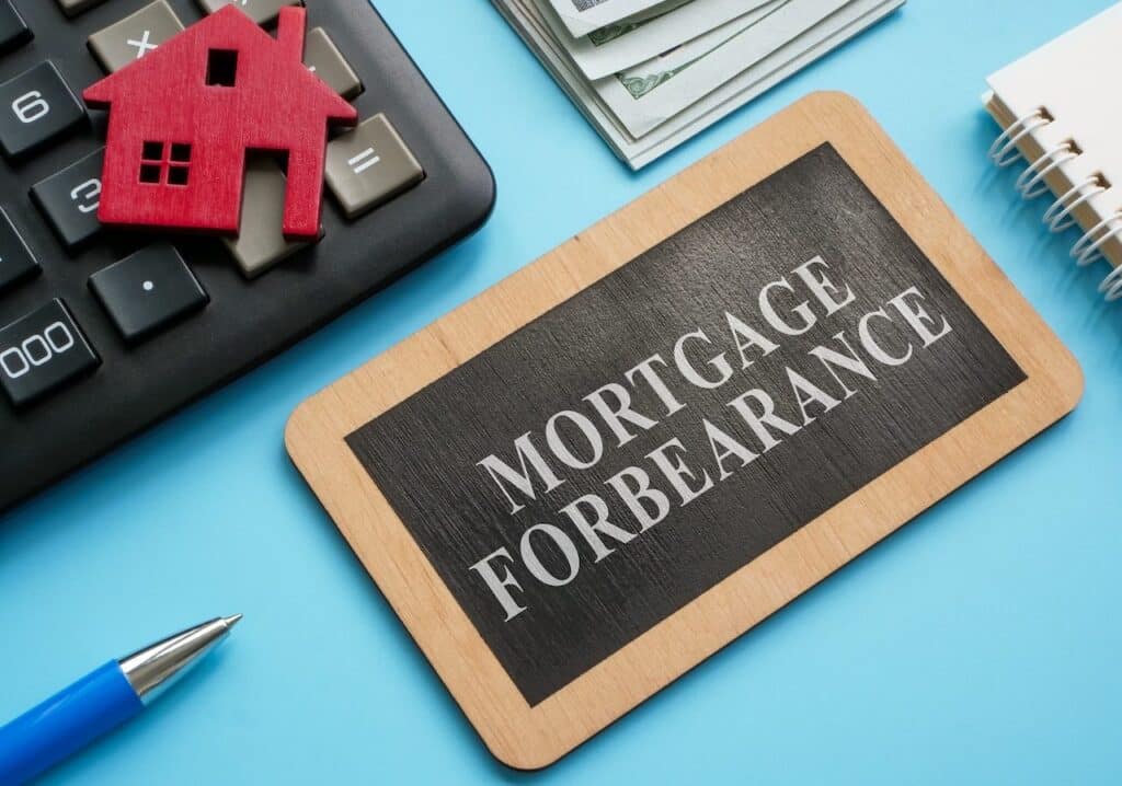 Wooden plate with inscription mortgage forbearance and model of house.