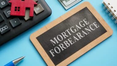 Wooden plate with inscription mortgage forbearance and model of house.