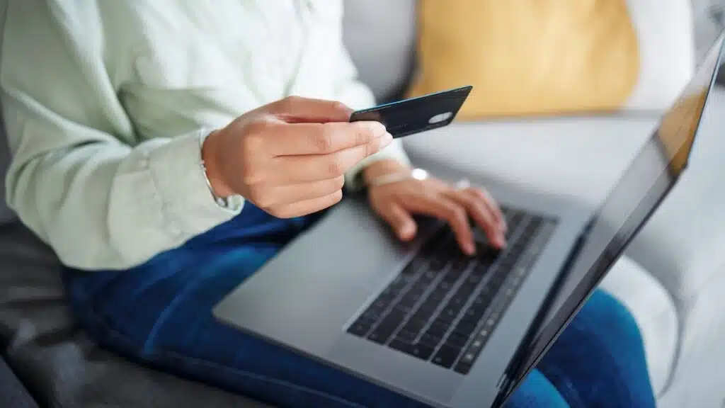 Hands, laptop and credit card for home online shopping, fintech payment and e commerce on sofa.