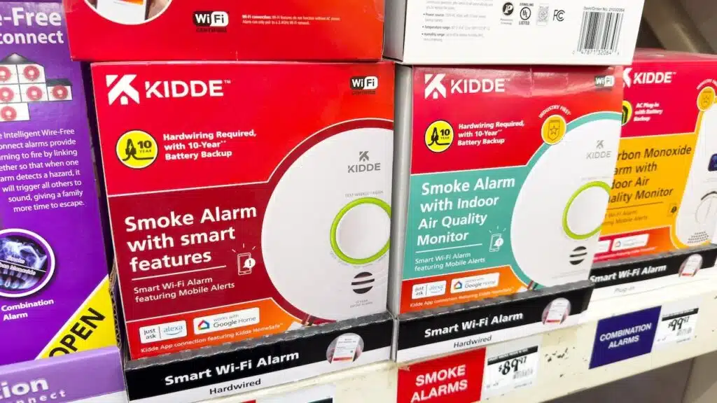 Kidde brand smoke alarms with smart features, hardwired versions on a shelf.