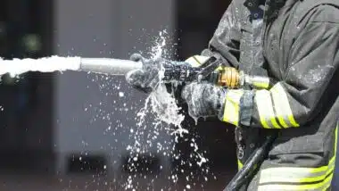 firefighter is spraying foam extinguishing agent with a powerful hose to control a fire during an emergency situation