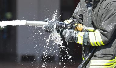 firefighter is spraying foam extinguishing agent with a powerful hose to control a fire during an emergency situation