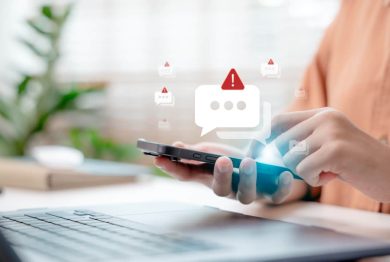 Close-up hand holding smartphone with spam alert icon popping up.