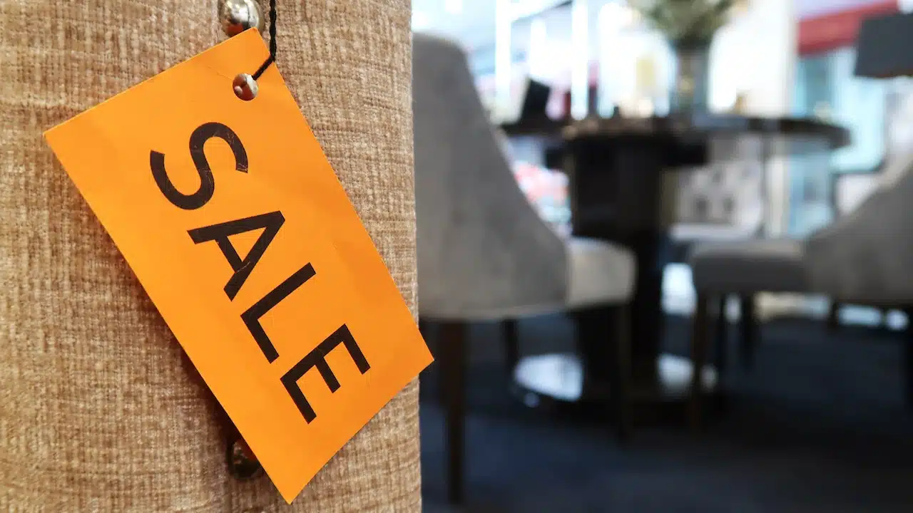 A yellow SALE tag on the sofa, with blurred furniture in the background