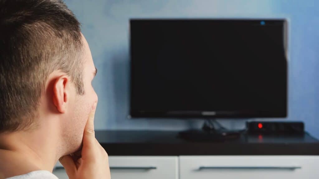 man trying to watching tv at home from back. TV is not working.