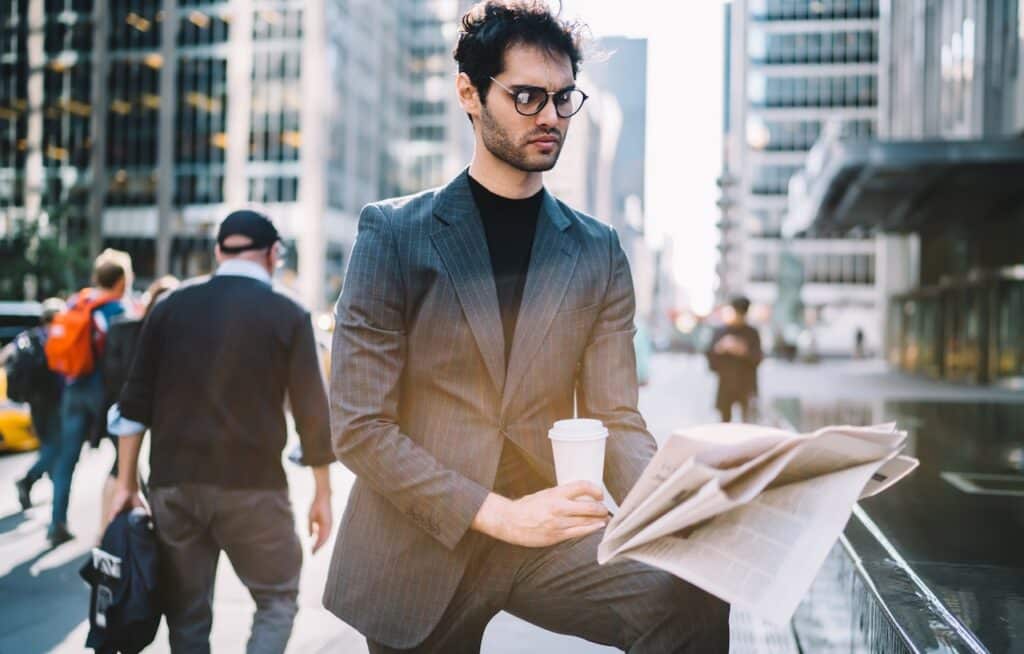Serious male 30s interested on publicated article in morning newspaper reading information during coffee time in Manhattan downtown.