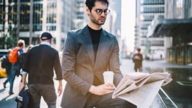 Serious male 30s interested on publicated article in morning newspaper reading information during coffee time in Manhattan downtown.