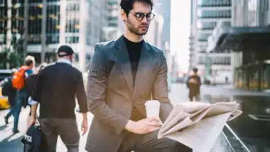 Serious male 30s interested on publicated article in morning newspaper reading information during coffee time in Manhattan downtown.
