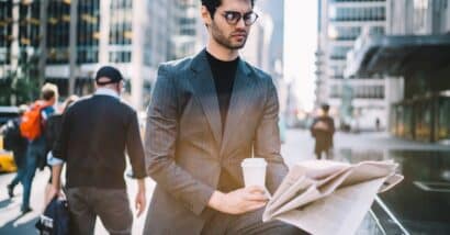 Serious male 30s interested on publicated article in morning newspaper reading information during coffee time in Manhattan downtown.