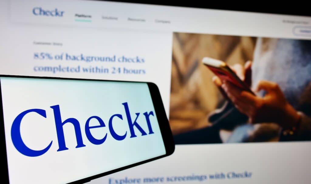 Mobile phone with logo of US background check company Checkr Inc on screen in front of website Focus on center-left of phone display