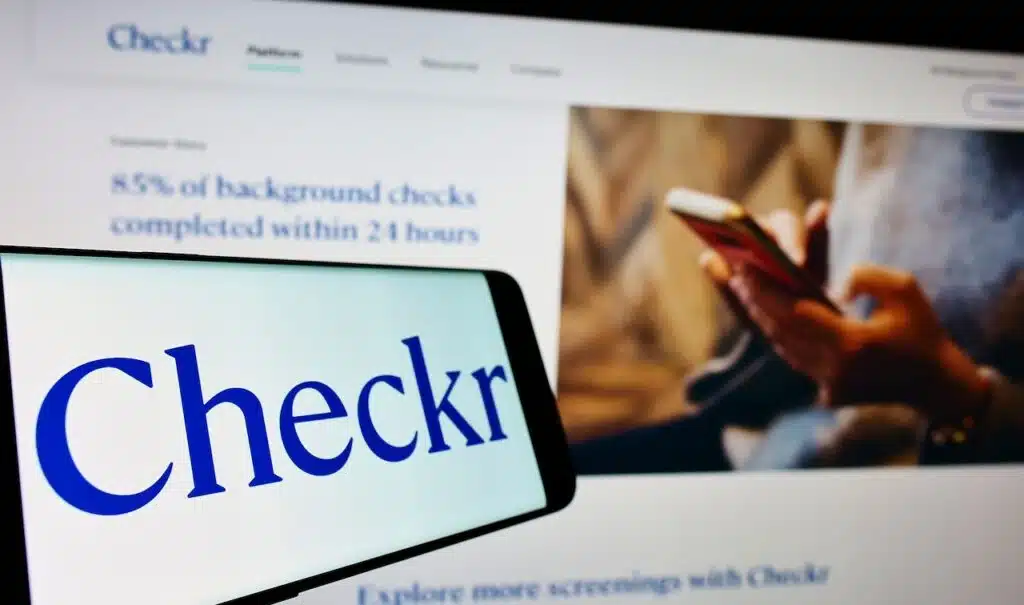 Mobile phone with logo of US background check company Checkr Inc on screen in front of website Focus on center-left of phone display