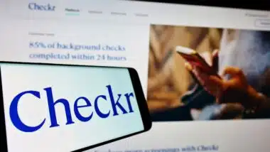 Mobile phone with logo of US background check company Checkr Inc on screen in front of website Focus on center-left of phone display