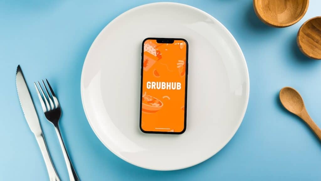 GrubHub food ordering and delivery app on smartphone screen on top of white plate.