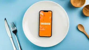 GrubHub food ordering and delivery app on smartphone screen on top of white plate.