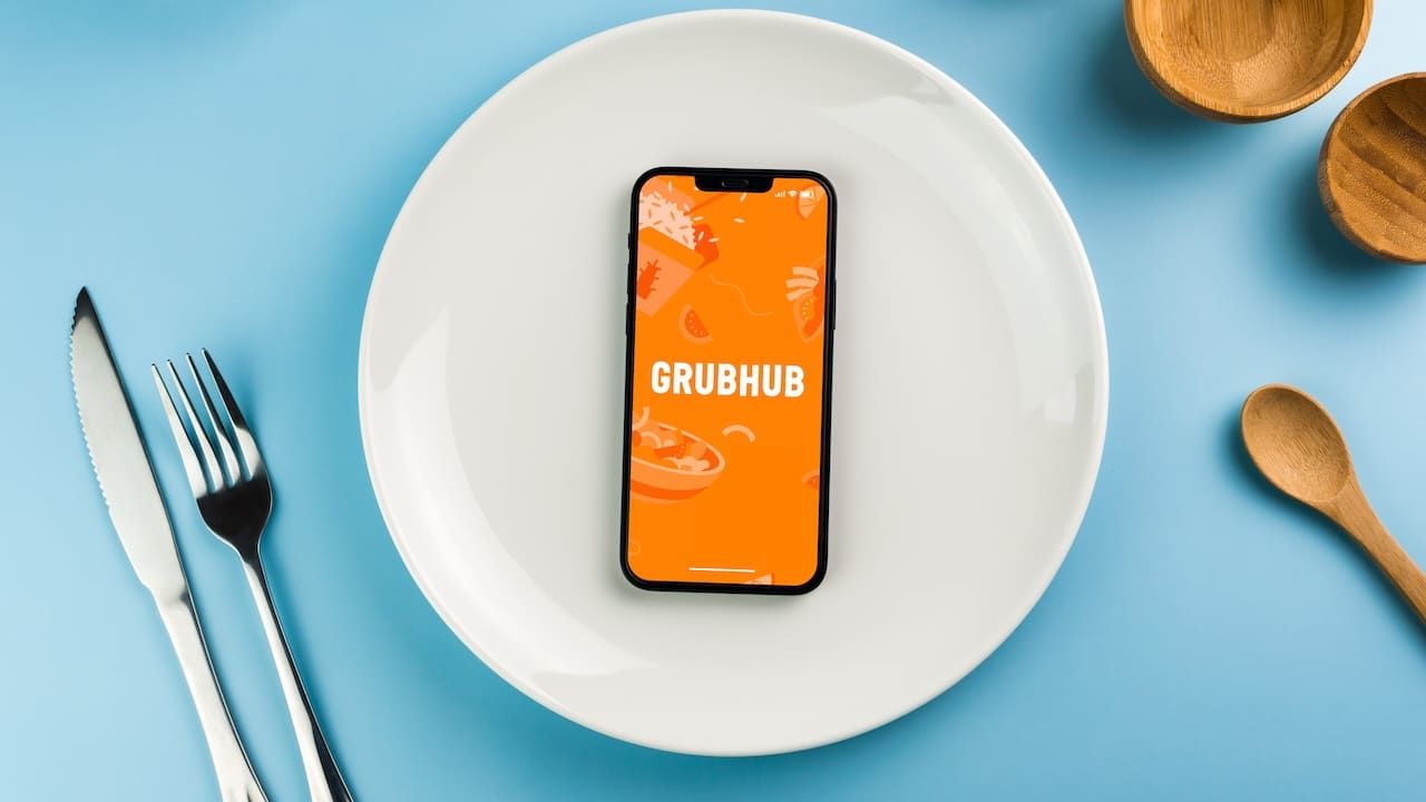GrubHub food ordering and delivery app on smartphone screen on top of white plate.
