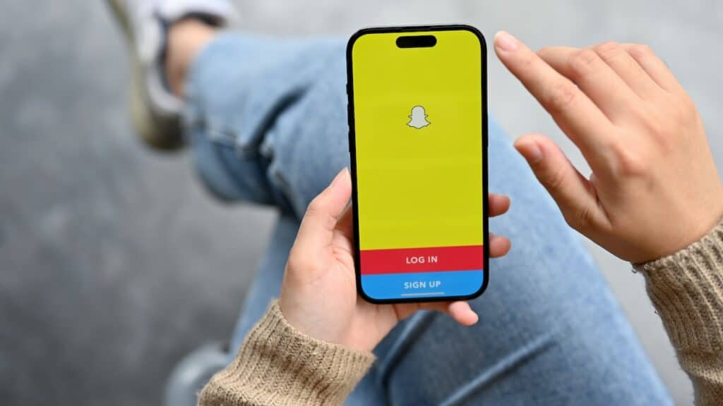 A female hand holding a smartphone with Snapchat application logo on screen. social media application