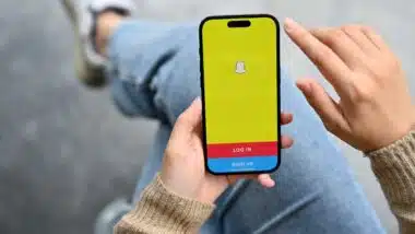 A female hand holding a smartphone with Snapchat application logo on screen. social media application