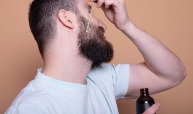 Closeup of male face and pipette with a oil for a beard growth.