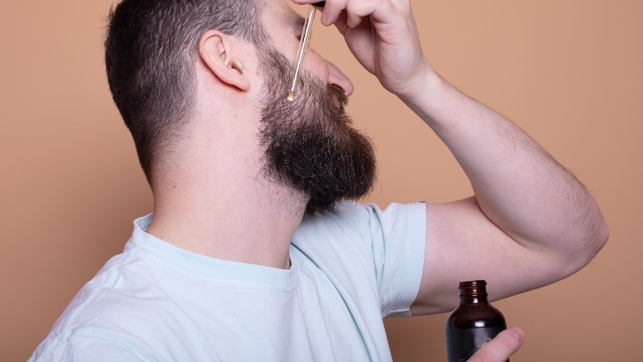 Closeup of male face and pipette with a oil for a beard growth.