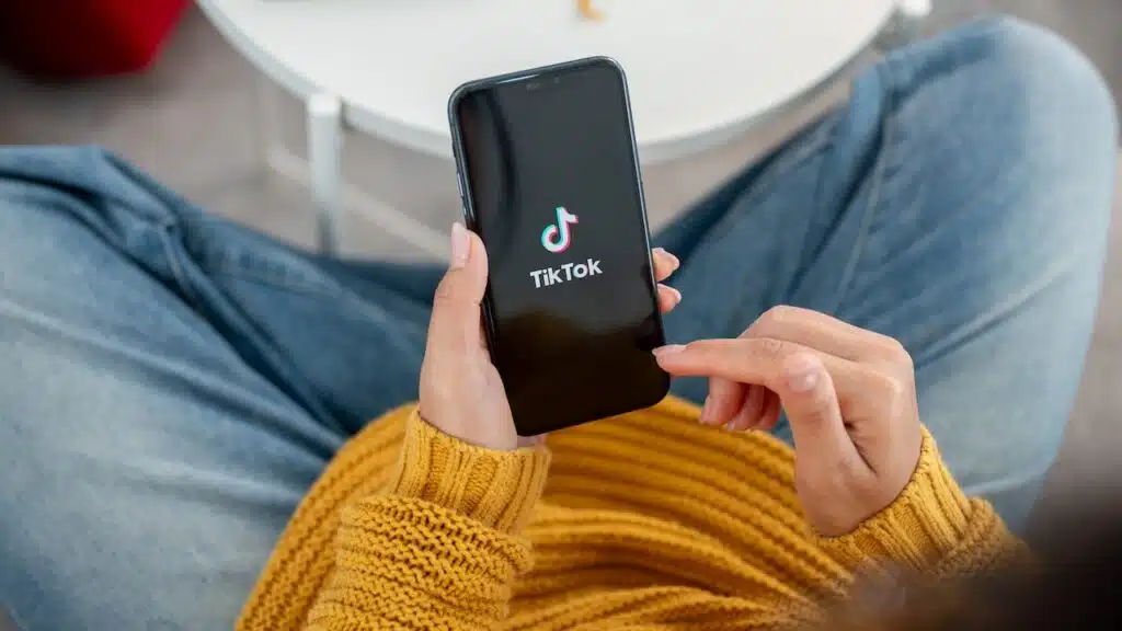 A close-up of a woman using the TikTok application on her iPhone