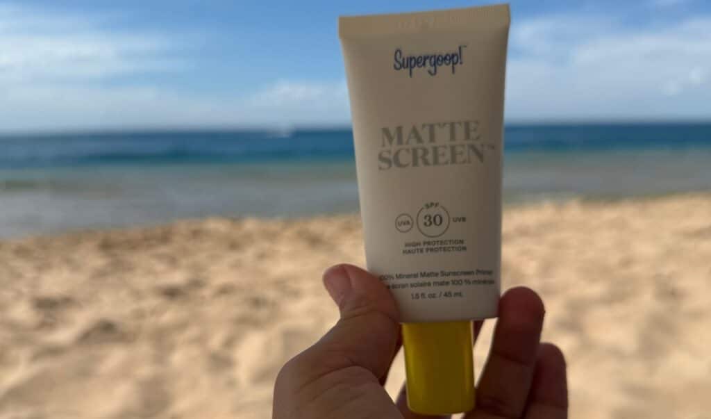 A bottle of Glow Recipe Tinted Serum and Supergoop Tinted Sunscreen at the Beach