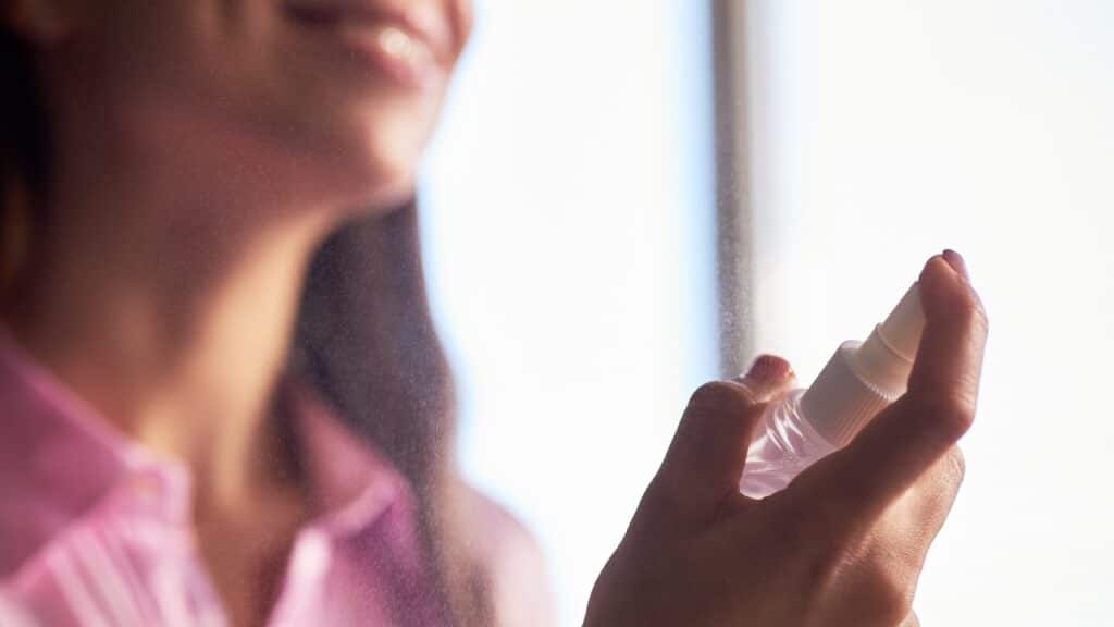 woman spraying facial mist onto skin during skincare routine