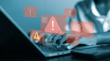 A person using a laptop with multiple red warning sign popups, symbolizing cyber security threats, data breach, or other security issues.
