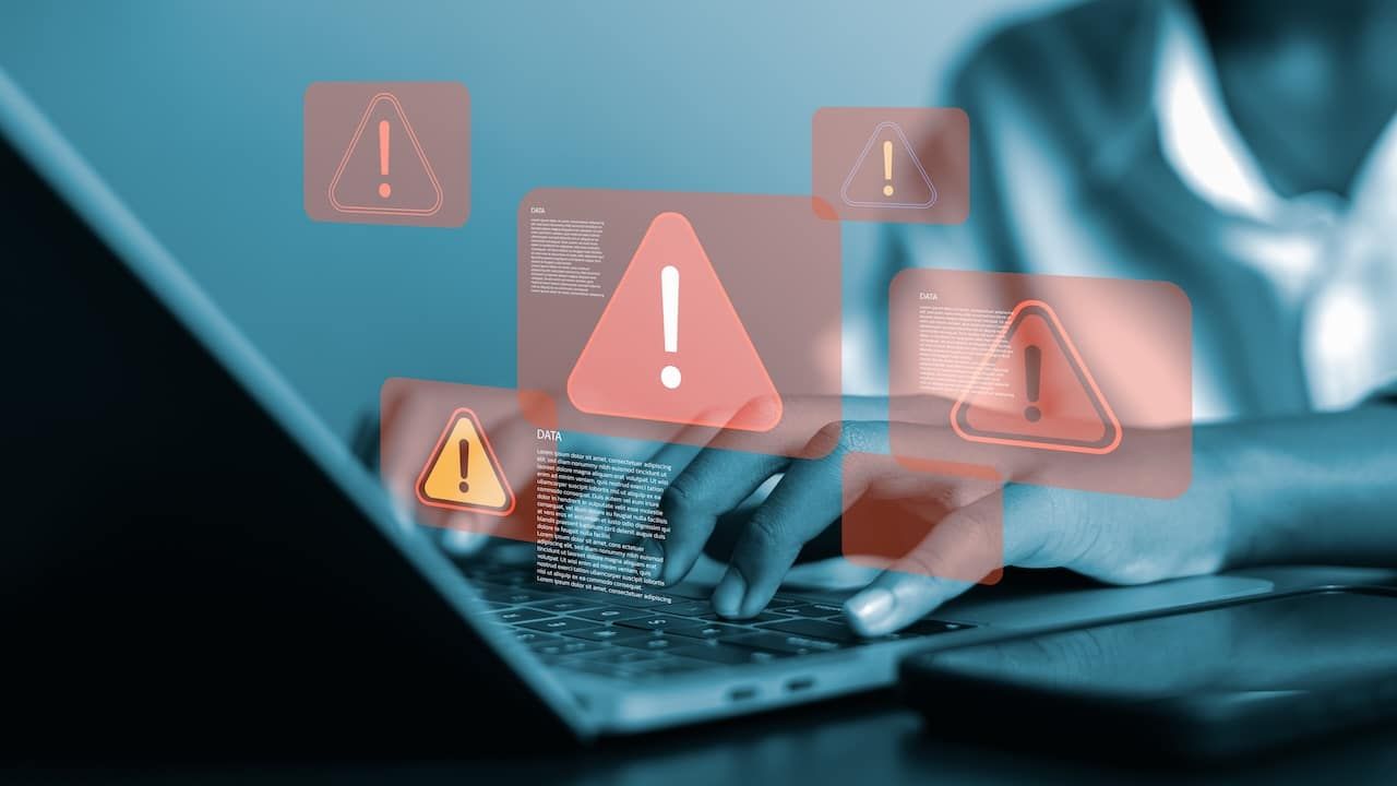 A person using a laptop with multiple red warning sign popups, symbolizing cyber security threats, data breach, or other security issues.