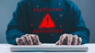 Person typing on keyboard with red warning