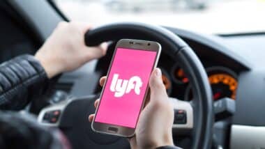 Lyft driver holding smartphone in car.