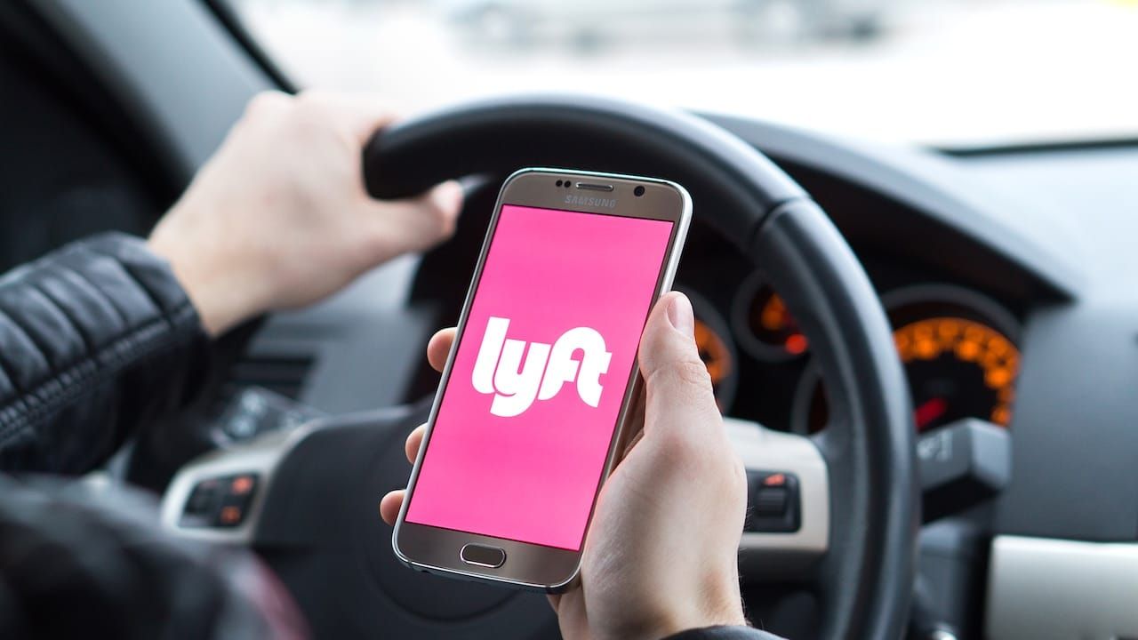 Lyft driver holding smartphone in car.