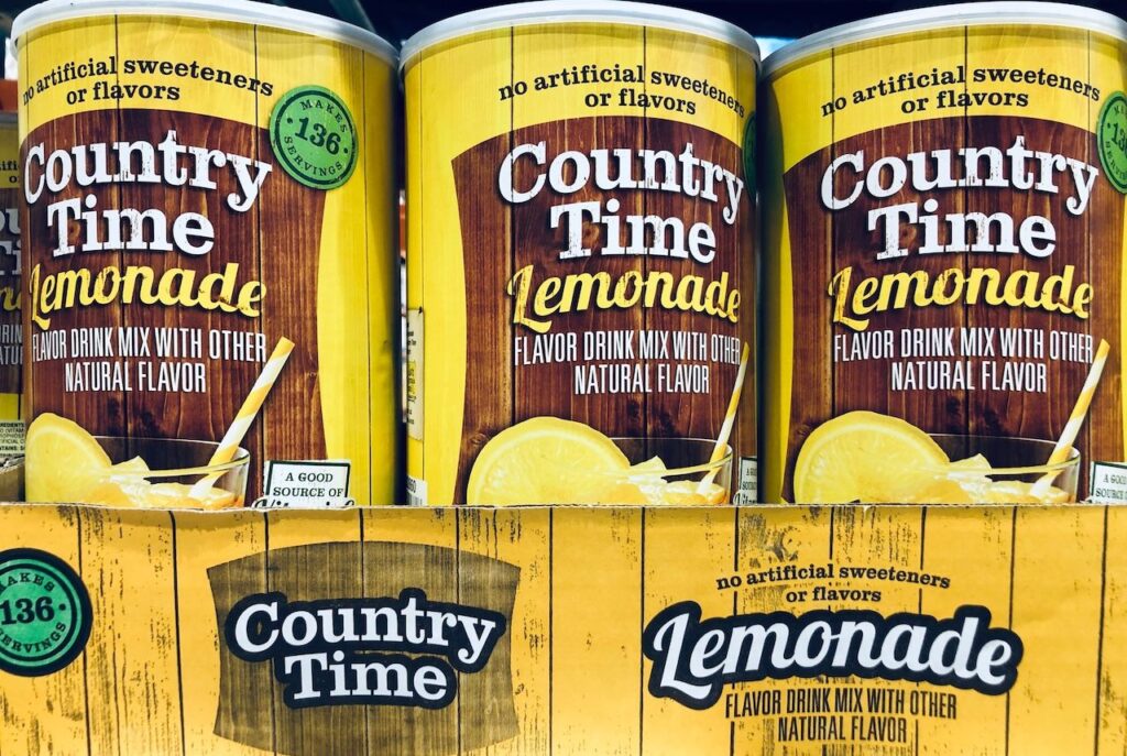 Large containers of Country Time Lemonade powdered drink mix for sale on a Costco Warehouse wholesale shelf.