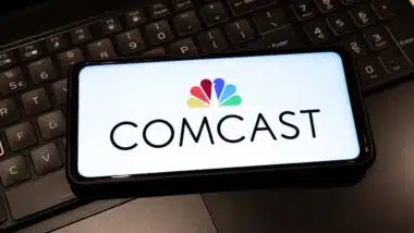 Comcast logo on mobile phone , background is a keyboard