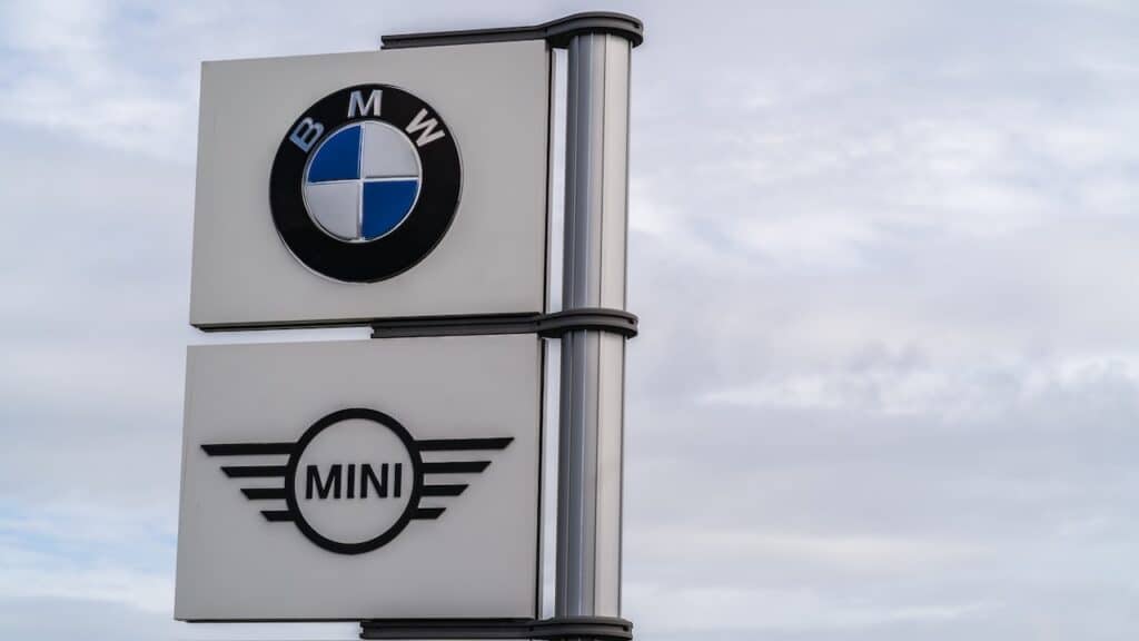 BMW and Mini logo signage against grey sky with clouds background