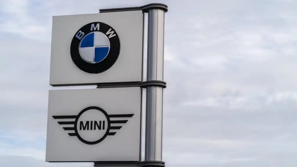 BMW and Mini logo signage against grey sky with clouds background