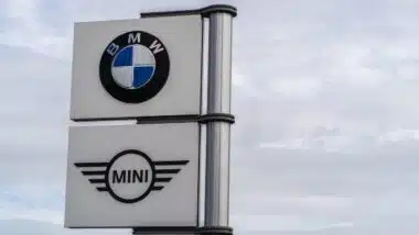 BMW and Mini logo signage against grey sky with clouds background