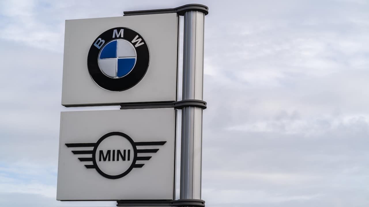 BMW and Mini logo signage against grey sky with clouds background