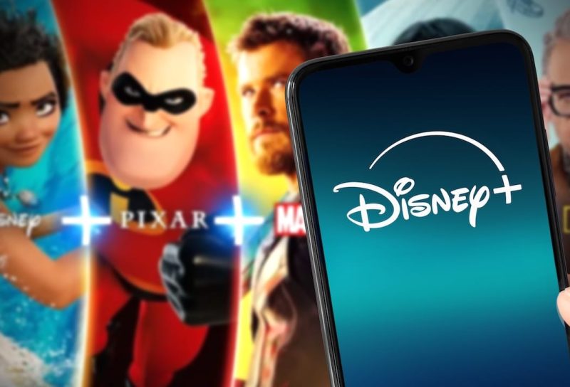 Smartphone with new Disney Plus logo with Disney Plus content on background