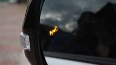 Car side mirror with illuminated orange blind spot monitoring warning indicator
