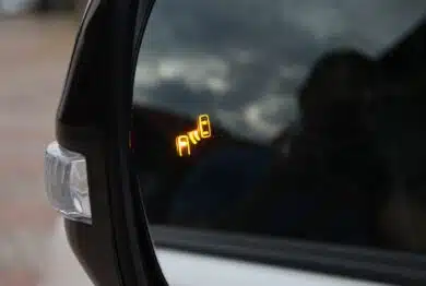 Car side mirror with illuminated orange blind spot monitoring warning indicator