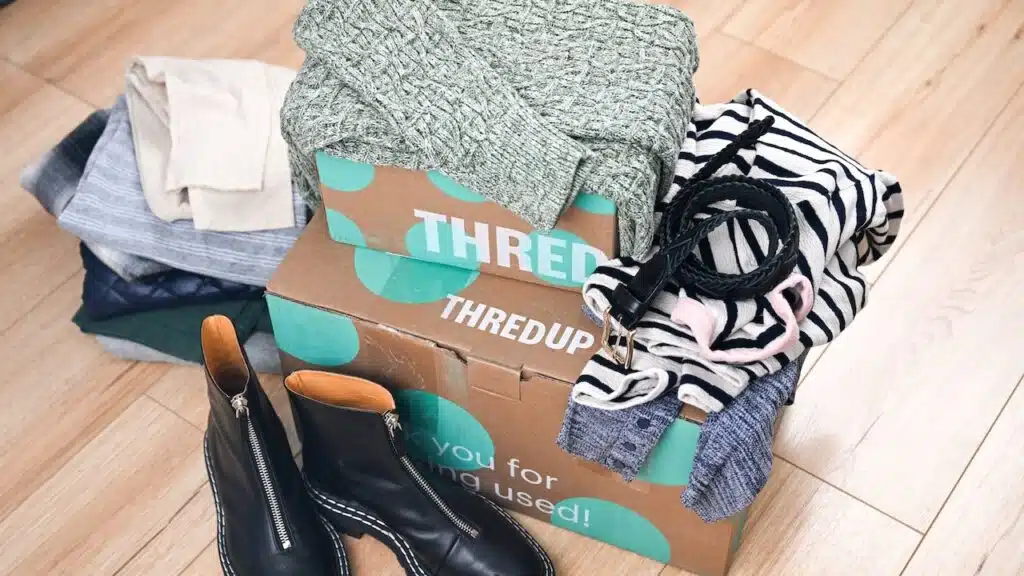 Delivery Boxes With Thredup Logo and Green Polka Dots Surrounded with Thrifted Clothing, Shoes, and Accessories