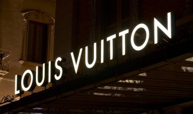 Illuminated Louis Vuitton signage suspended over a store