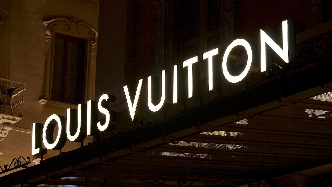 Illuminated Louis Vuitton signage suspended over a store