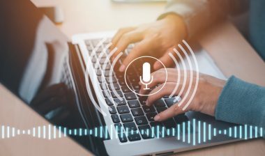 Businessman using laptop with microphone button on virtual screen.