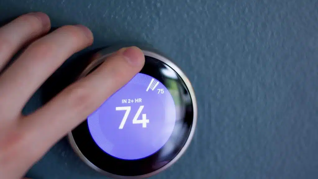 Finger touching Smart thermostat to adjust temperature