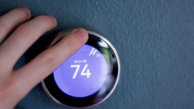 Finger touching Smart thermostat to adjust temperature