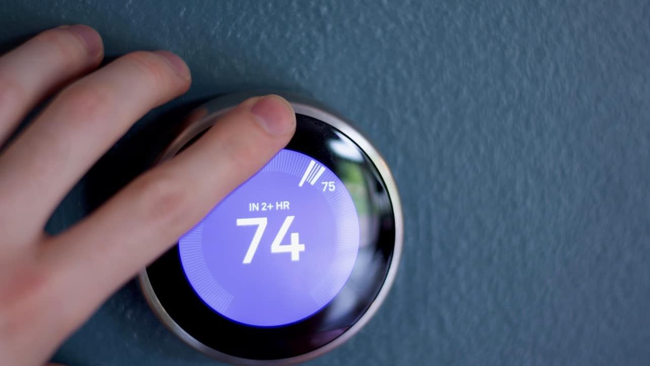 Finger touching Smart thermostat to adjust temperature