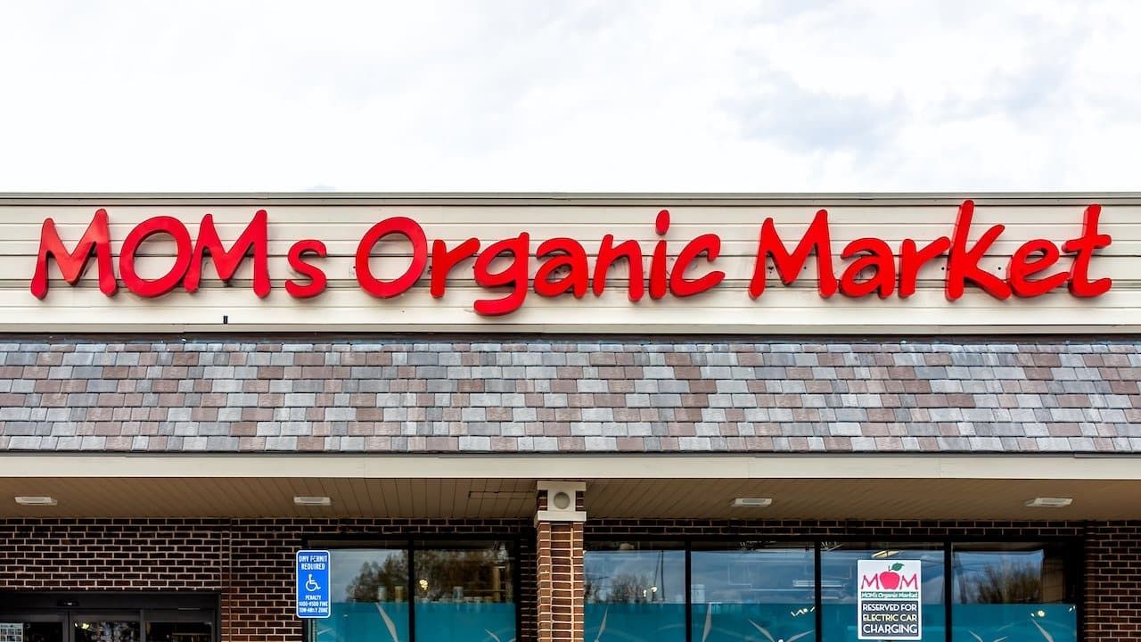 Exterior facade of Mom's Organic Market store with farm fresh produce on street