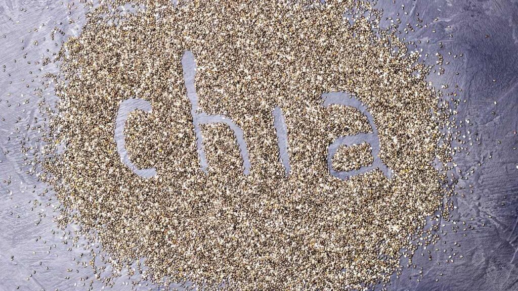 dark Chia seeds with Chia inscription on a black stone background.